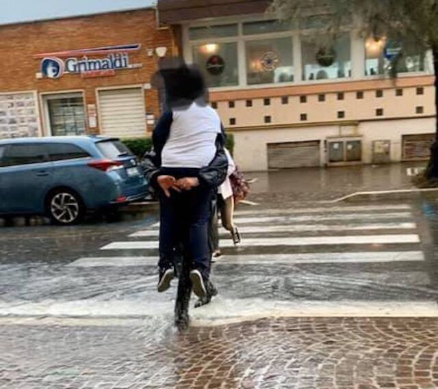 nettuno vigile prende in braccio i bambini sulle strisce pedonali allagate