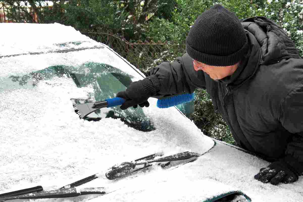 Uomo toglie il ghiaccio dal parabrezza