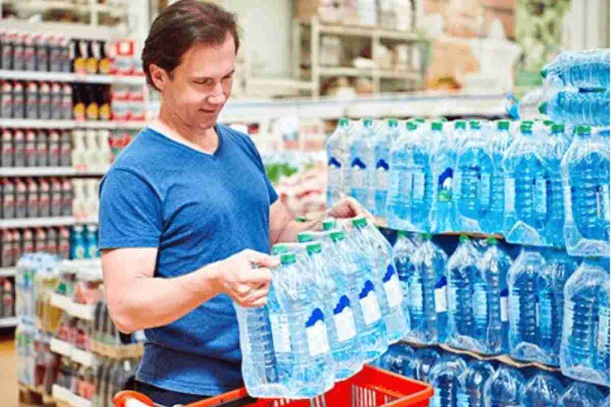 Uomo compra l'acqua al supermercato