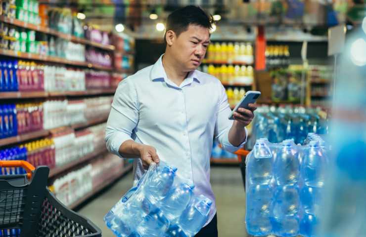 Cliente al supermercato con la cassa d'acqua