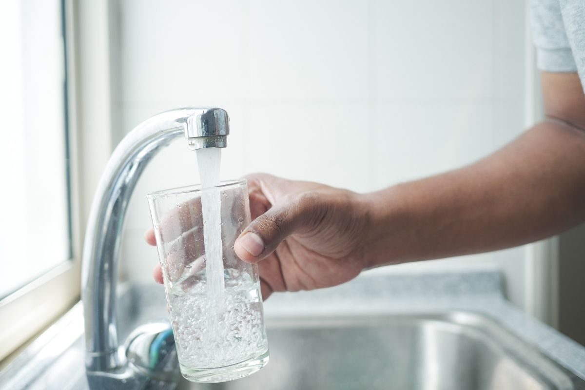 Persona prende un bicchiere d'acqua dal rubinetto